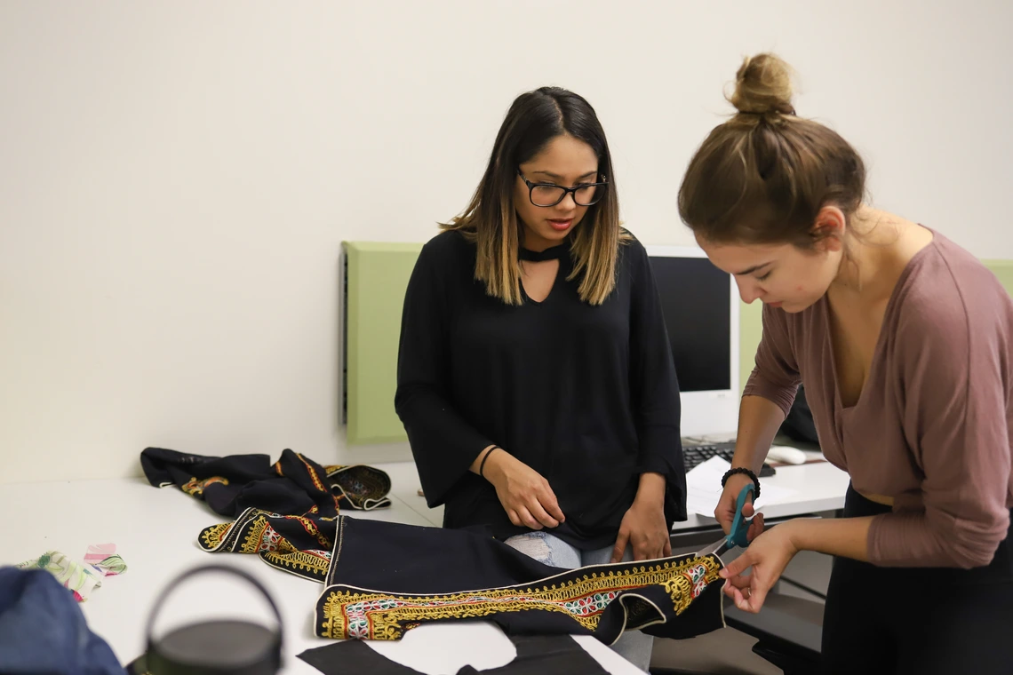 Two women modifying a garment together