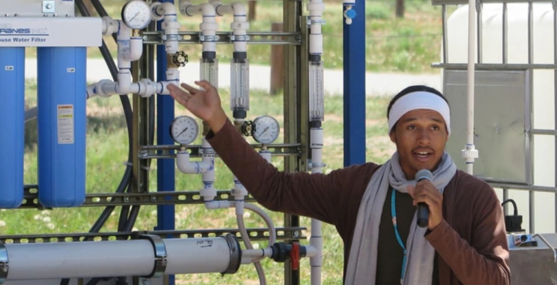Student giving a talk in front of a water filtration system