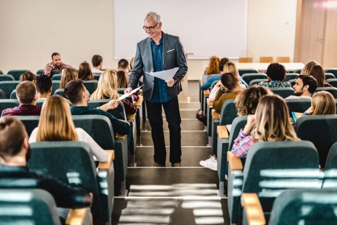 An instructor handing out sheets to students in a lecture hall