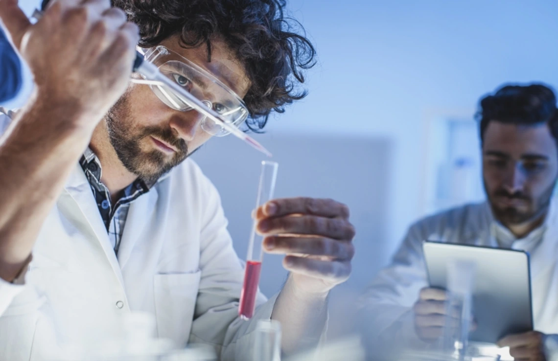 A scientist carefully adding a chemical to a test tube