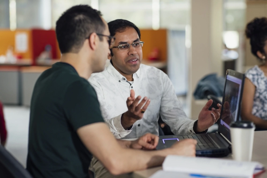 Two people discussing a project while looking at a laptop screen