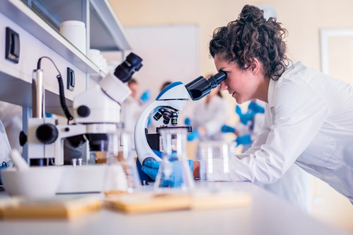 woman looking at a lab sample through a microscope