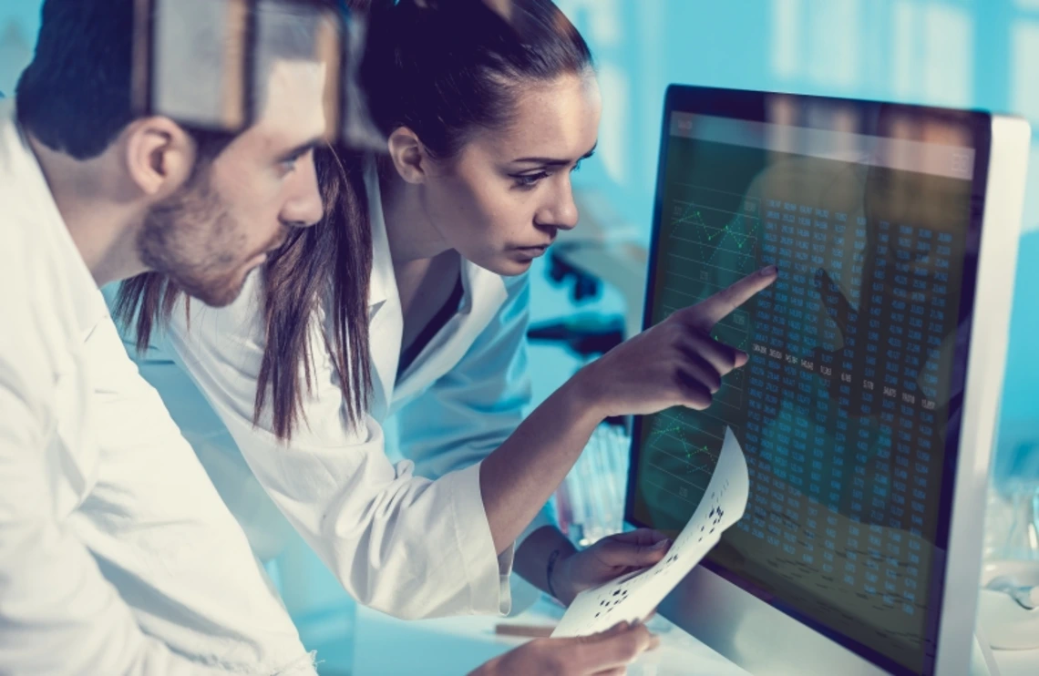 Two researchers looking at data on a computer screen together