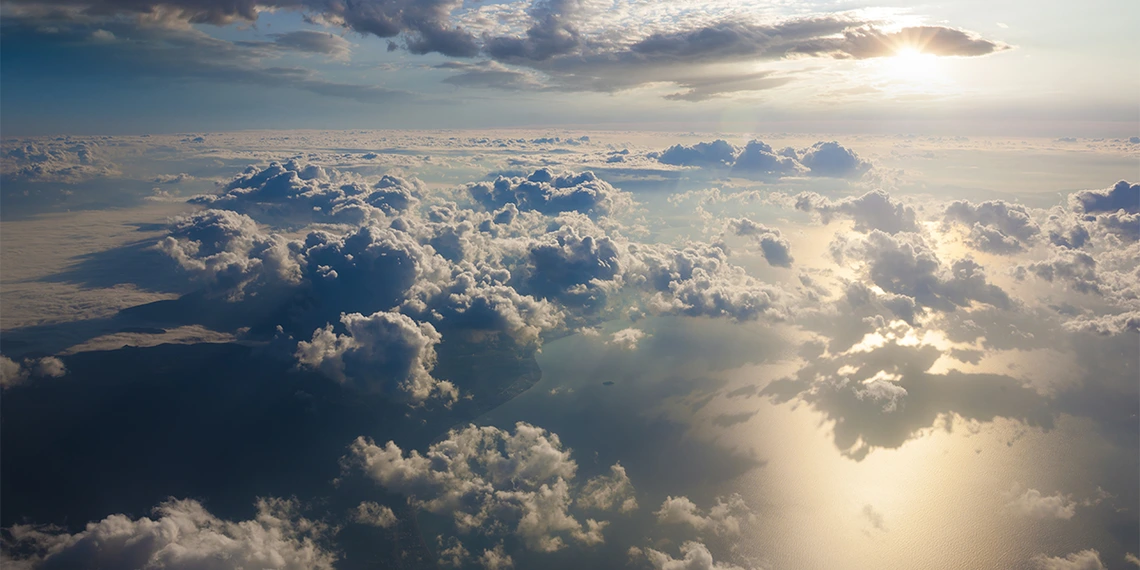 Clouds above a large body of water with sunlight reflecting off the water