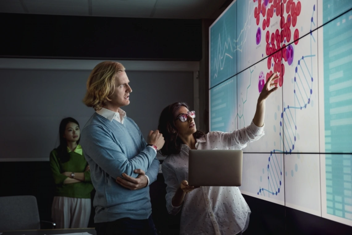 Researchers examining a chart on a screen in a dark conference room
