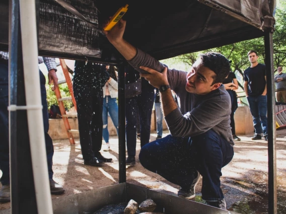 A man using a tool to inspect a structure he's kneeling under