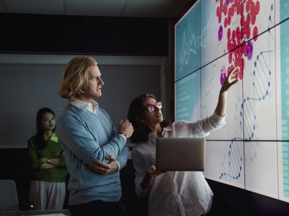 Researchers examining a chart on a screen in a dark conference room