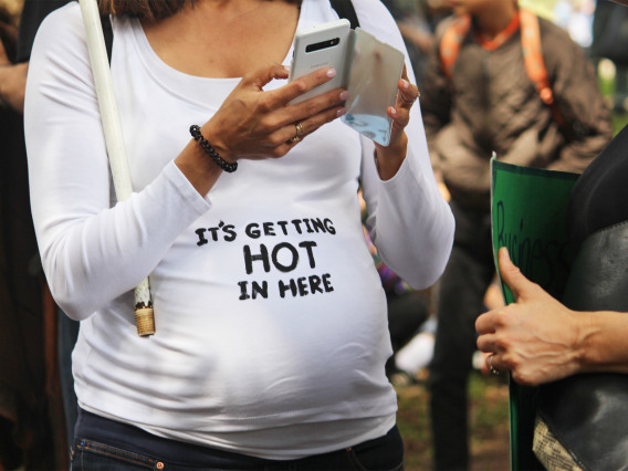 pregnant woman at a rally with a T-shirt reading "It's getting hot in here"