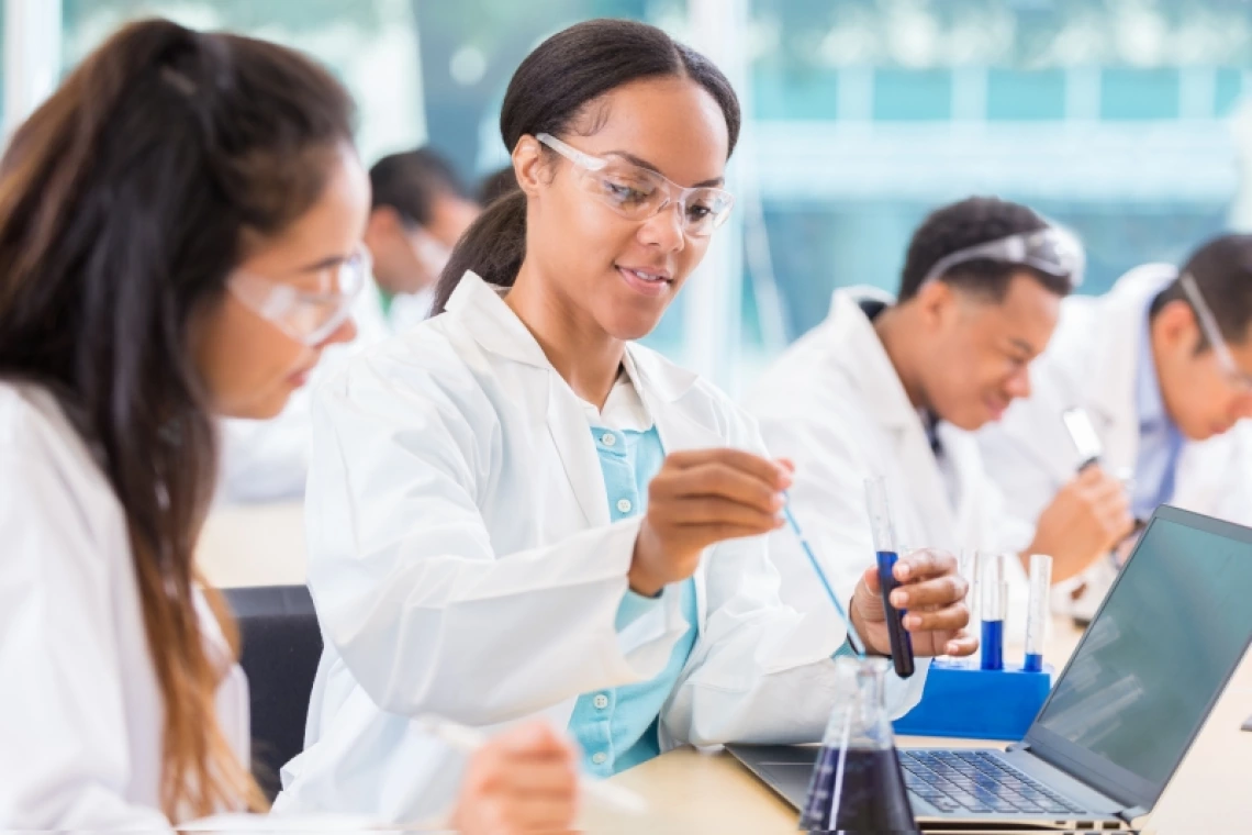 Researchers working with a sample together next to a laptop