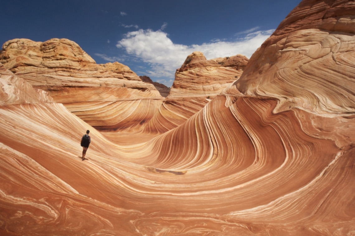 Adult male tourist hikes across the striated sandstone rock formations known as the Wave