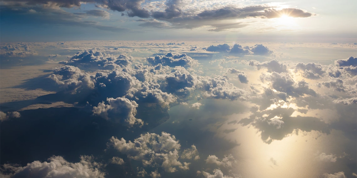 Clouds above a large body of water with sunlight reflecting off the water