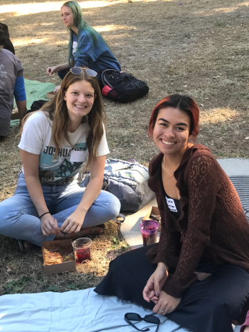 Two students sitting in the grass and smiling