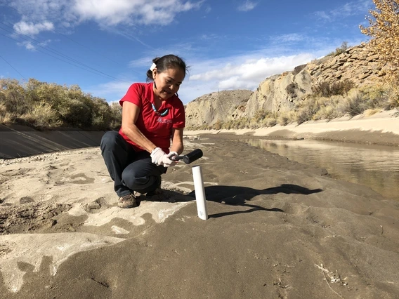 Karletta Chief using a tool to conduct hydrological fieldwork in a riverbed